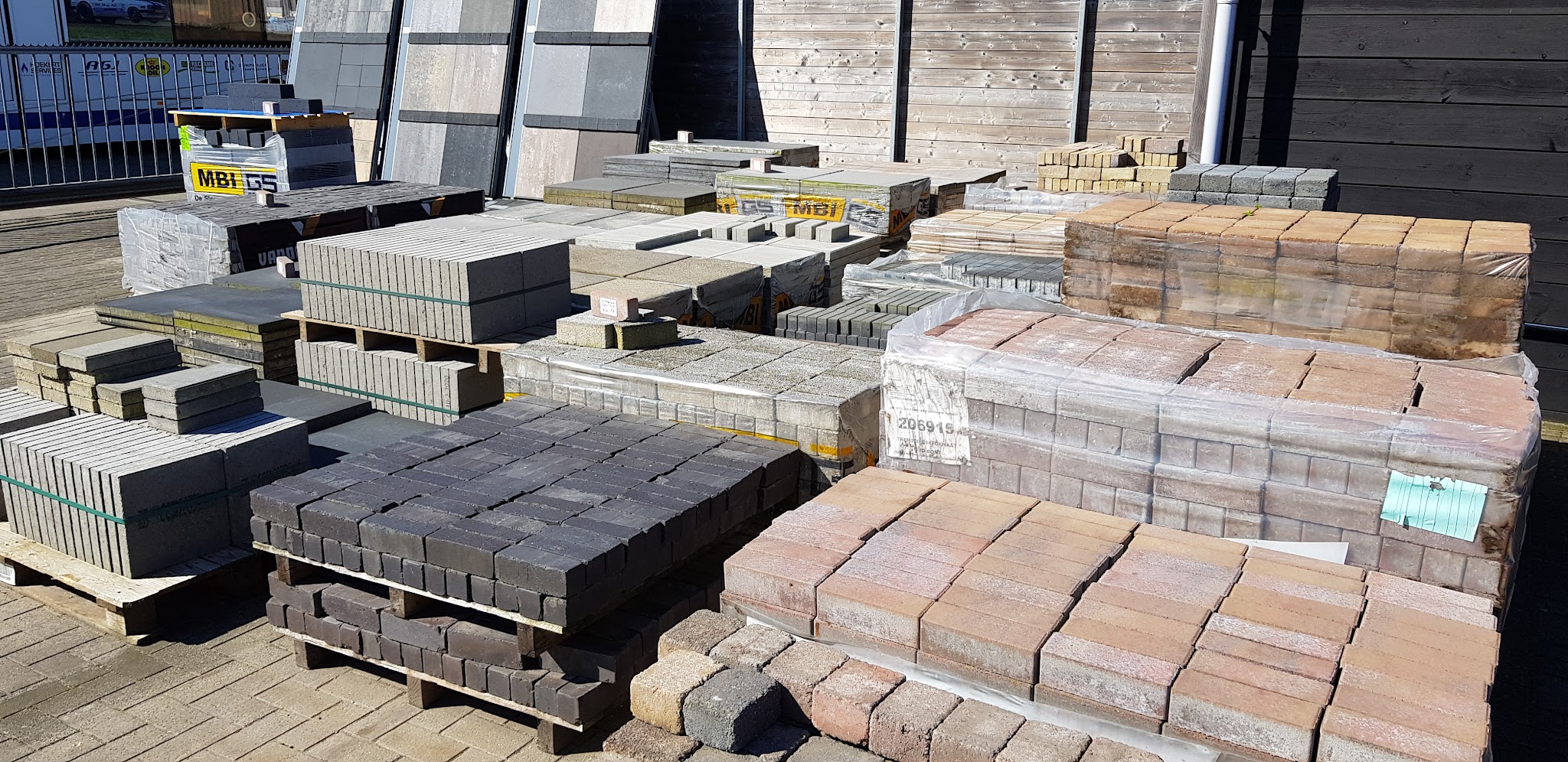 Pallets met klinkers en tegels op het terrein van Fleming Infra in de zon