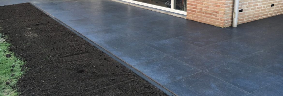 Keramische tegels worden gelegd langs een woning aan de Klokbekerweg in Epe